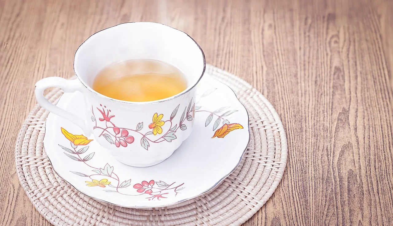 Tazza di tè tiepido fumante su un tavolo, ideale per bruciare grassi addominali al mattino.